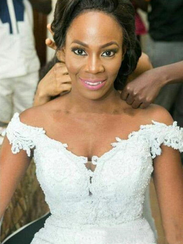 Vestidos de novia de tul con hombros descubiertos, apliques, sin mangas y cola larga.